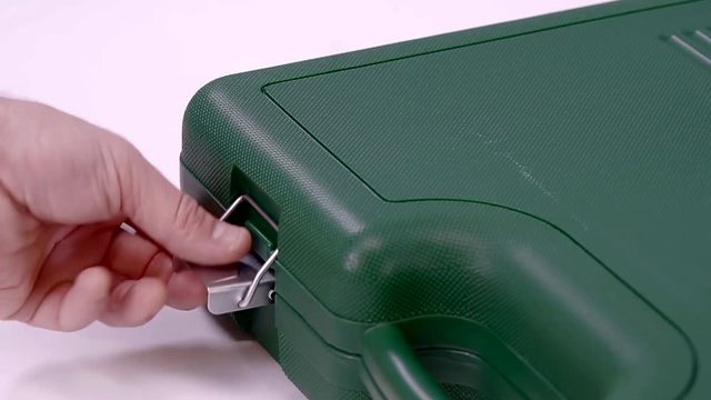 close up shot of the man's hands, who closes the suitcase with the tools, he clicks the clasp with his fingers