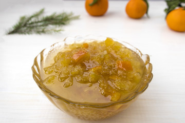 Sweet jam, tangerines and spruce branch located on a light table.