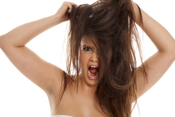 Angry young woman pulls her hair on white background