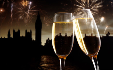 celebrating new year's eve in the city - toasting with champagne glasses in front of Big Ben- holiday lights and fireworks in the background