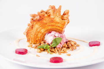 Polish-Lithuanian traditional spit cake ('tree cake') -sekacz (polish) or sakotis (lithuanian) with ice-cream, roasted nuts and raspberry jelly decorated wtih fresh mint