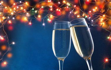 two champagne glasses ready to bring in the New Year - holiday lights and fireworks in the background