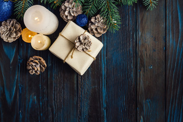 Christmas and Christmas decorations Pine branches of a tree, cones, blue Christmas toys on a wooden background.primary packaging and candles