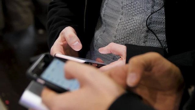 Close-up of smartphones in hands of two young men . New generation in a cafe in close up. Communication concept. Couple using digital gadgets for online shopping, chatting, blogging, surfing internet