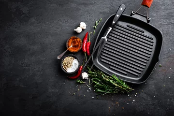 Wandaufkleber Empty cast-iron grill pan with ingredients for cooking on black background, top view © Sea Wave