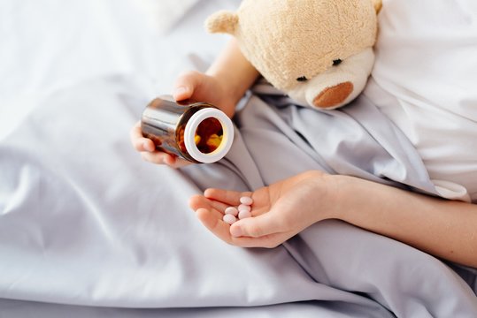 Child taking medicines pills.