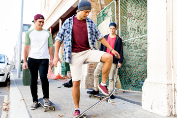 Teenage friends walking at the street with skateboards