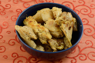 Sauteed chicken thighs in blue bowl on festive red  holiday tablecloth