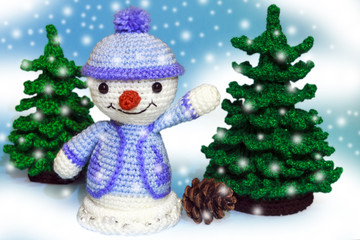 cheerful toy snowman in the snow near the Christmas tree waving his hand