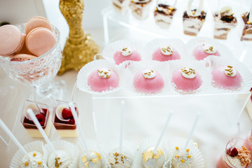 Delicious wedding reception candy bar dessert table full with cakes and sweets and a flower vase with hydrangeas on the background of an exquisite restaurant.