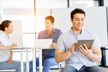 Young handsome businessman using his touchpad sitting in office