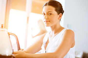 Naklejka premium Happy young woman with cup of tea or coffee at home