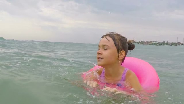 The child learns to swim. A little girl is swimming in the sea in an inflatable circle.