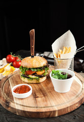 Vegetarian burger with French fries and salad on a wooden board