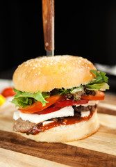 Burger with wheat loaf, French fries and salad on a wooden board