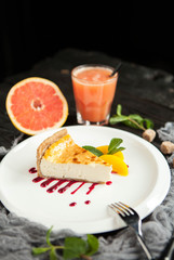 Cheesecake with berry sauce, peach and a glass of grapefruit juice on a wooden background