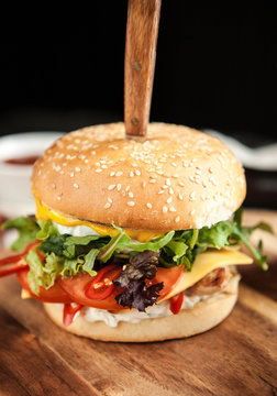 Burger with wheat loaf, French fries and salad on a wooden board