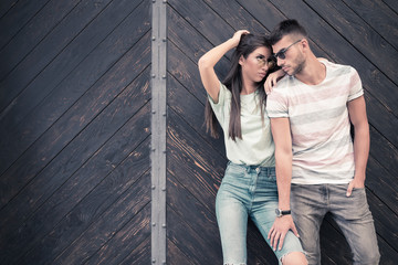 Young beautiful fashionable couple posing against wooden gate
