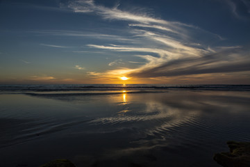 Fototapeta na wymiar Sun setting at beach at low tide in San Diego, California