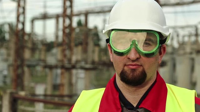 Power engineering specialist in goggles and hard hat at heat power plant. Worker in green goggles on electric station looks at the camera
