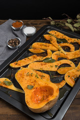 Preparation of butternut pumpkin sliced with salt, sweet pepper, pepper and thyme in baking dish