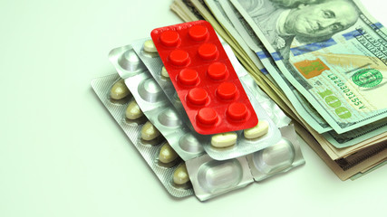 Money bills mixed with medication pills on a table.