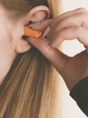 Woman putting ear plugs into ears