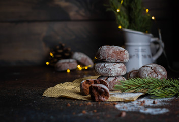 Deliciouse Homemade Chocolate crinkle cookies with powdered sugar icing on dark stone table background. Holiday Decoration, lights, garland