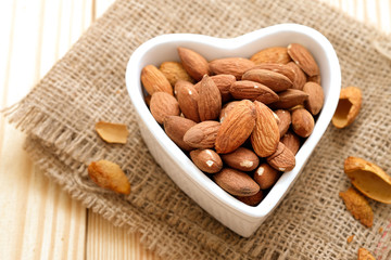 Almond nuts in the shell In a heart shaped bowl on sackcloth and wooden floor