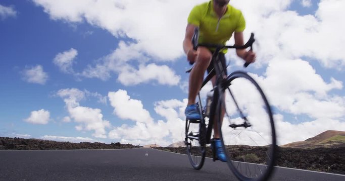 Road cycling cyclist man biking on professional road bike. Sports fitness video of athlete riding racing bike on road. Active healthy sports lifestyle athlete cycling. SLOW MOTION, RED EPIC.