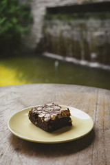 Chocolate brownie in plate on wooden table.