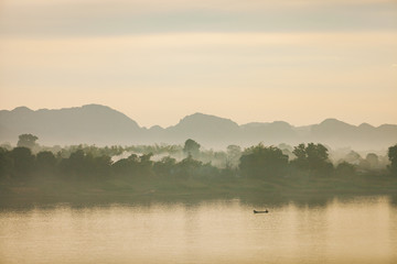 Fisherman floats on a lake at the morning.