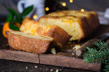 Homemade Citrus Tangerine cake decorated with caramelized slices of mandarin tangerine on stone table background. Close up Christmas holiday cake with festive decor lights and garland.