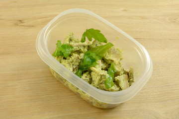 Pesto chicken salad packed in plastic storage container for lunch at work or on the go