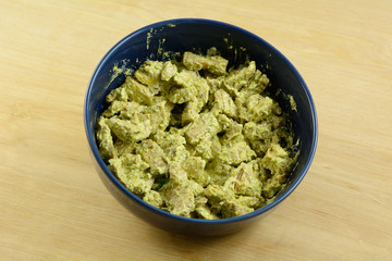 Pesto chicken salad in blue bowl on wooden table