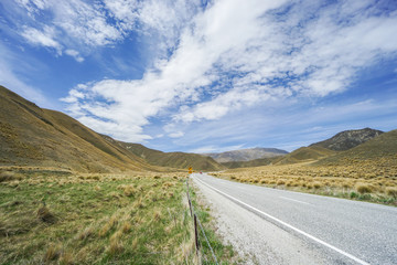 landscape and concrete road of Lindis Pass with bright blue sky in autumn