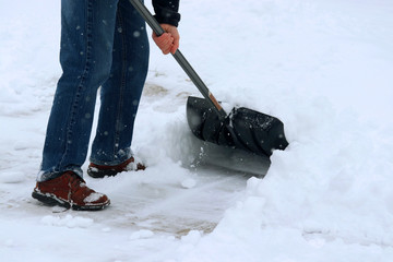 Winter snowy day background. Man shoveling snow on driveway during a heavy snowfall. Close up...