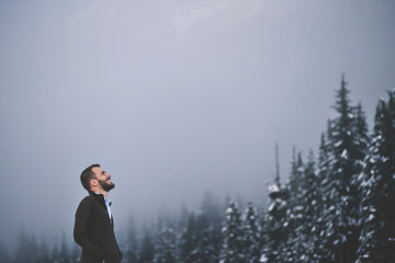 Hiker contemplating in front of foggy forest landscape