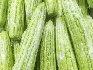 Closeup surface pile of fresh green bitter cucumber in plastic rap for sell textured background