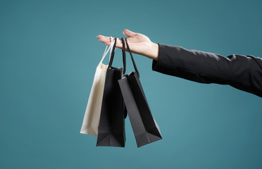Close up of man hand with shopping bags , isolated on light blue background .