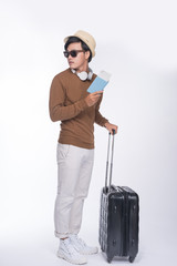 Full length of young tourist asian man holding passport with suitcase over grey background