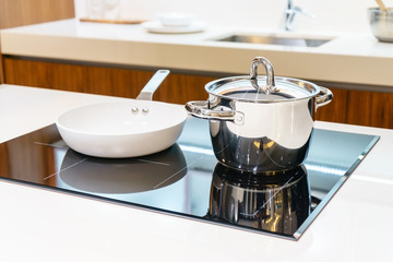 Close-up of stainless steel cooking pot and pan on induction hob in modern kitchen. modern kitchen pot cooking induction electrical stove hob concept