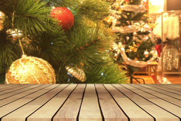 Perspective empty wooden table and christmas tree with snowing and blur decoration at coffee shop background, for product display montage or design layout.