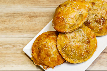 Round mini meat pies on a plate on a table.