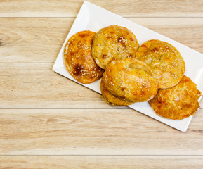Round mini meat pies on a plate on a table.