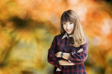 Attractive asian woman in plaid shirt and blue jeans standing with crossed arms