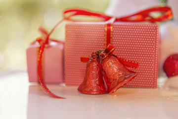 Christmas gift box, red jingle bell and blurred fir tree against blue bokeh background.