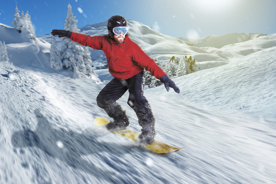 Snowboarder fährt bergab in sonniger Winterlandschaft