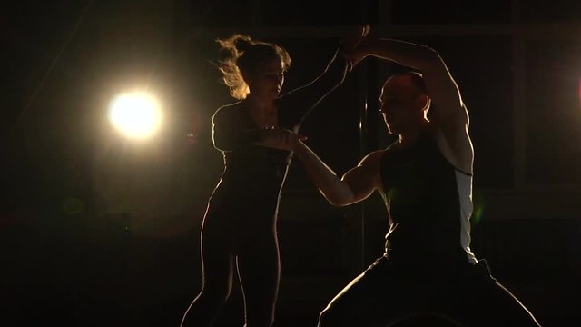 The man gently supports the woman beauty and she makes a coup in the air, slow motion