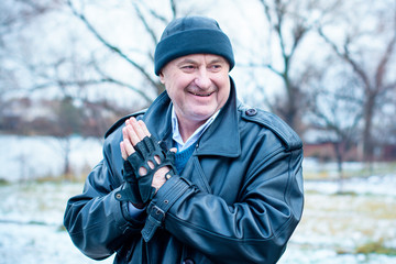 American Mature Happy Man Smiling with good mood at nature outside. Portrait of happy elderly man against winter forest background on a travelling 